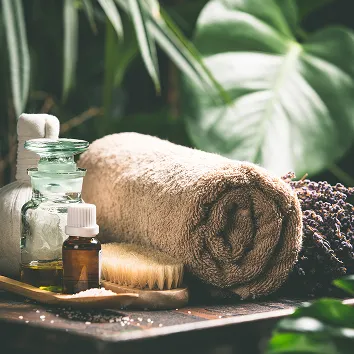 モンステラの葉を背景にした、落ち着いた雰囲気のスパ用品とアロマのボトル。