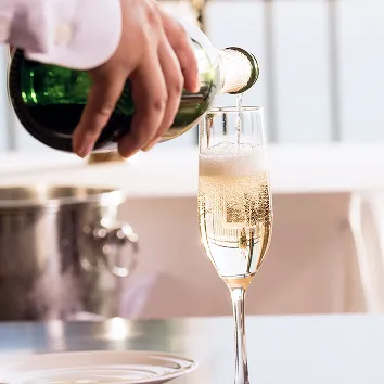 フルートグラスに黄金色のシャンパンを注ぐ様子。